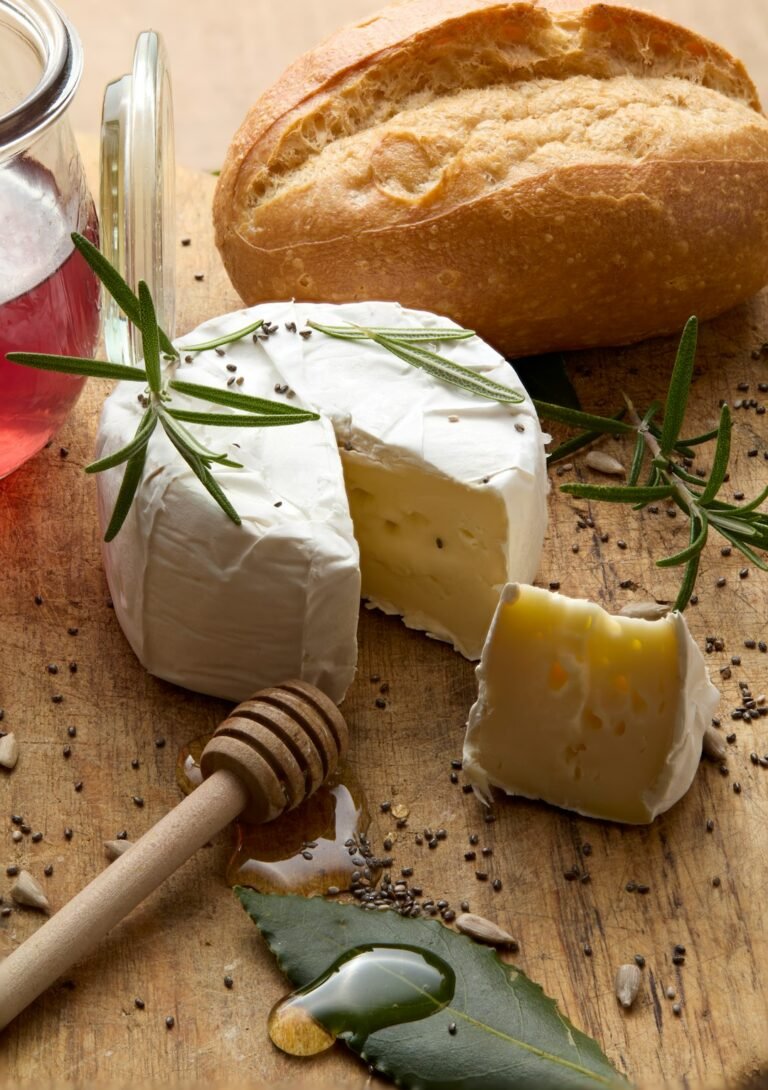 Queijo Camembert inteiro com uma fatia cortada, mel e alecrim