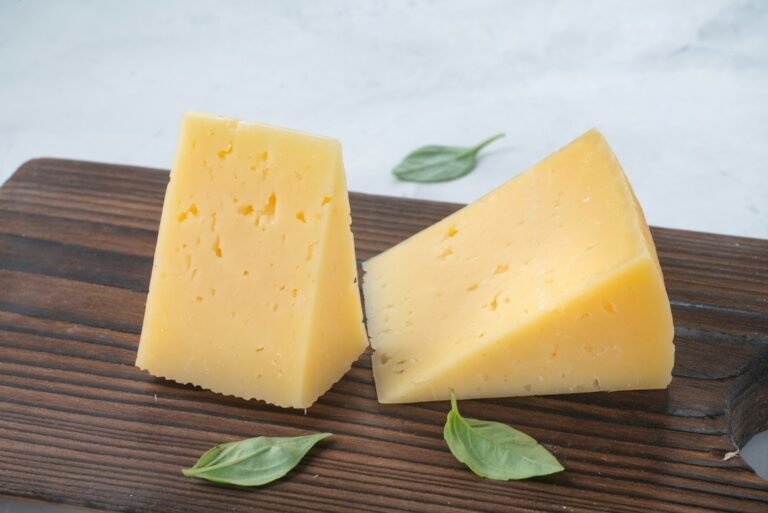 Pedaços de queijo duro curado sobre tábua de madeira
